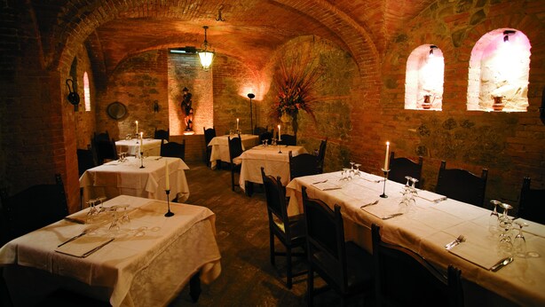 A dimly lit restaurant with brick arches and candle-lit tables. - Alla Rocca Hotel (Valsamoggia)