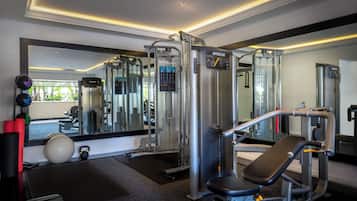 Une salle de sport équipée de divers appareils d’exercice, dotée d’un mur avec des miroirs et offrant une vue sur l’extérieur.