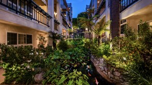 Une cour avec un bassin à carpes koï, une végétation luxuriante et des immeubles à plusieurs étages dotés de balcons.