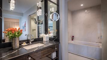 Un baño moderno con un espejo grande, un tocador con lavabo y una bañera.