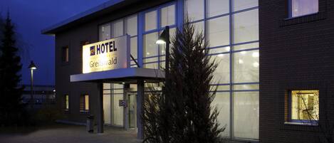 A modern hotel building with large windows and a sign indicating it is the Greiswald Hotel.