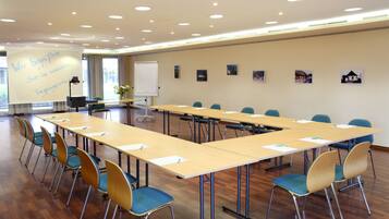 A conference room with a long table, chairs, a projector screen, and a whiteboard.