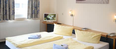 A hotel room with two beds, a flat-screen TV, a bedside lamp, and a painting on the wall.