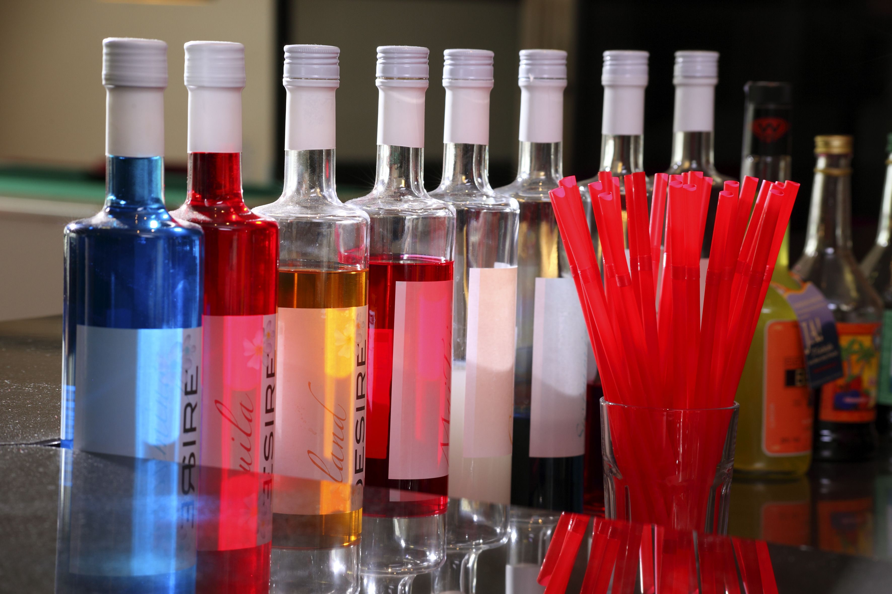 Una barra con varias botellas de alcohol y pajitas rojas.