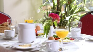 A breakfast setting with a table set for two, including plates, cups, a pitcher, and a glass of orange juice. - VCH Hotel Greifswald (Greifswald)