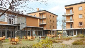 A courtyard with outdoor seating, a staircase, and modern brick buildings. - VCH Hotel Greifswald (Greifswald)