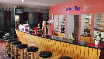 A bar area with stools, a counter, and shelves with glasses and bottles.
