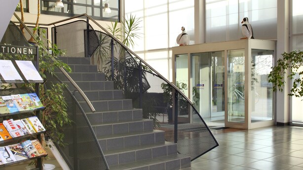A spacious lobby with a staircase, large windows, and a reception area. - VCH Hotel Greifswald (Greifswald)