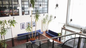 A spacious lobby with a blue sofa, potted plants, and hanging pendant lights. - VCH Hotel Greifswald (Greifswald)