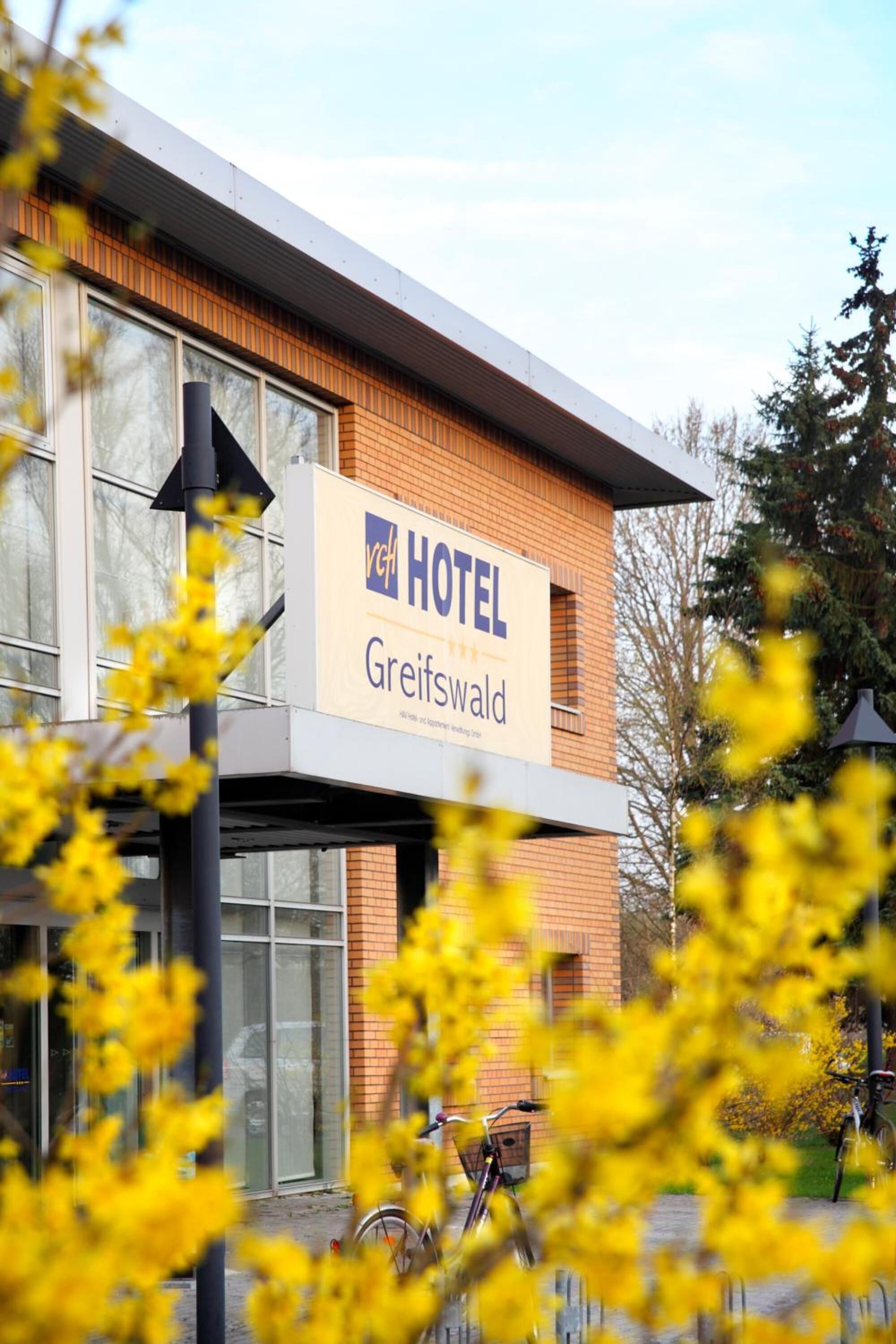Een hotelschilt met de naam 'Hotel Greifswald' en een modern gevelontwerp.