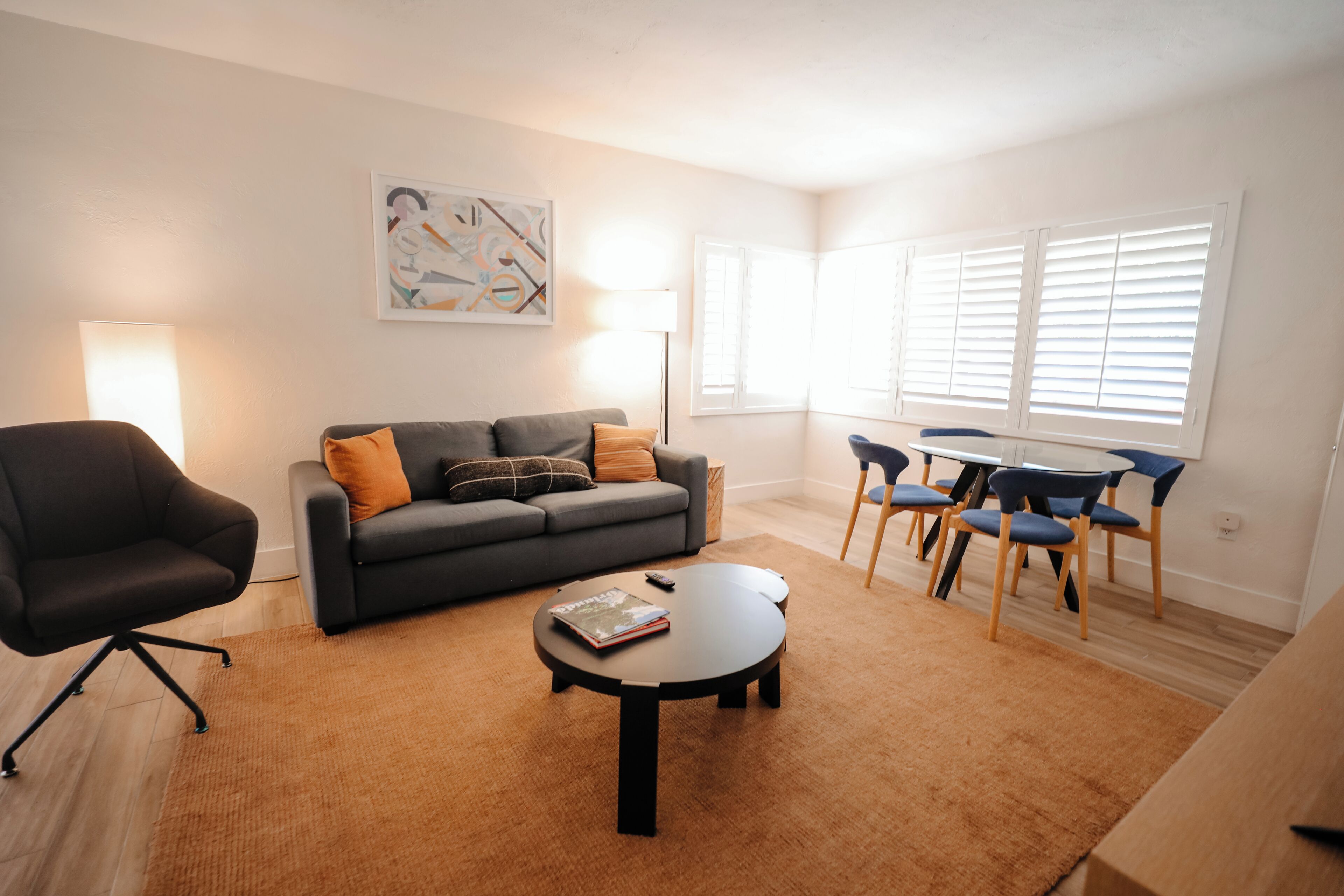 Un salon comprenant un canapé, une table basse, un fauteuil et une table à manger avec des chaises.