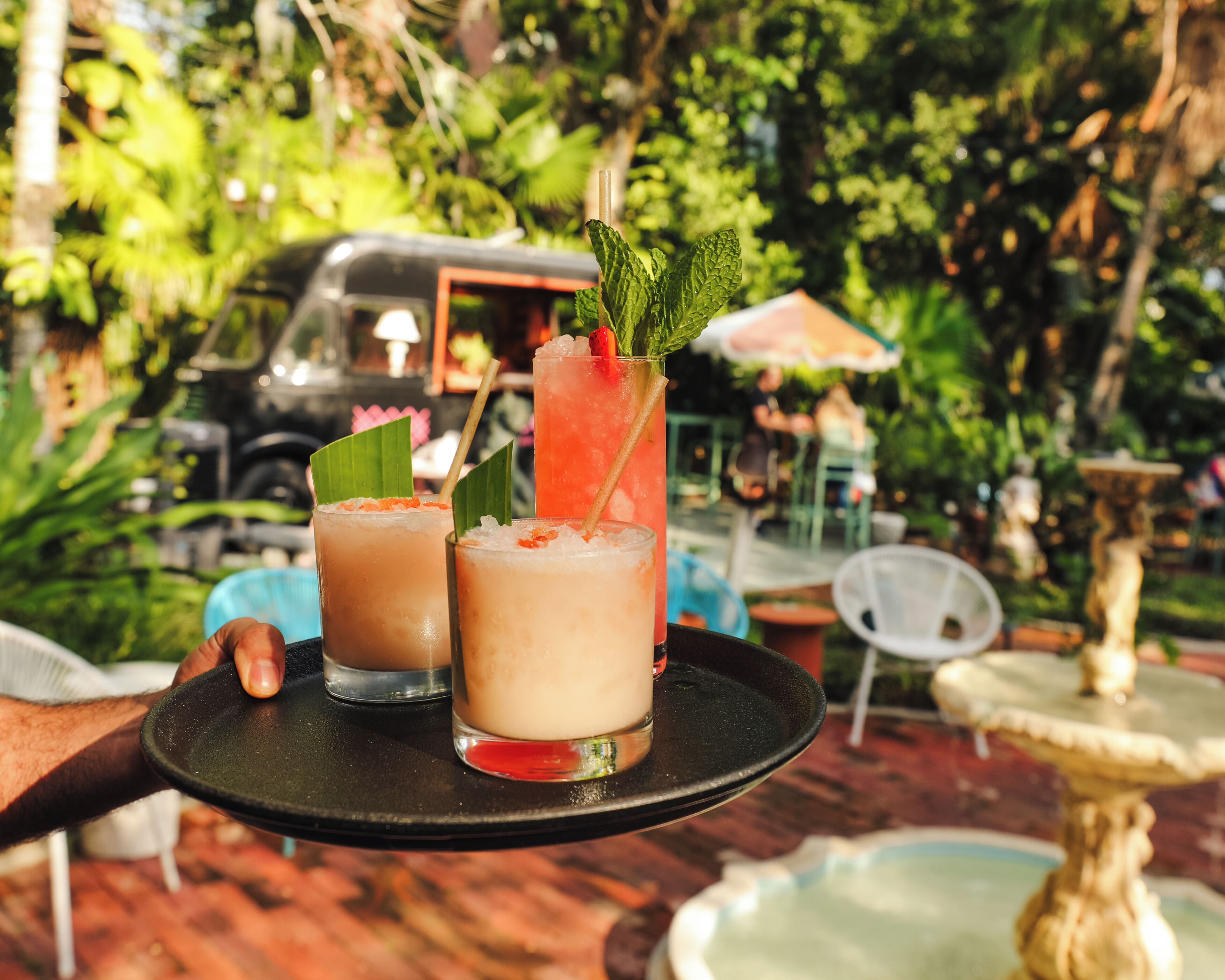 Un plateau avec deux boissons, l’une décorée d’une fraise et de feuilles de menthe, et un véhicule en arrière-plan.