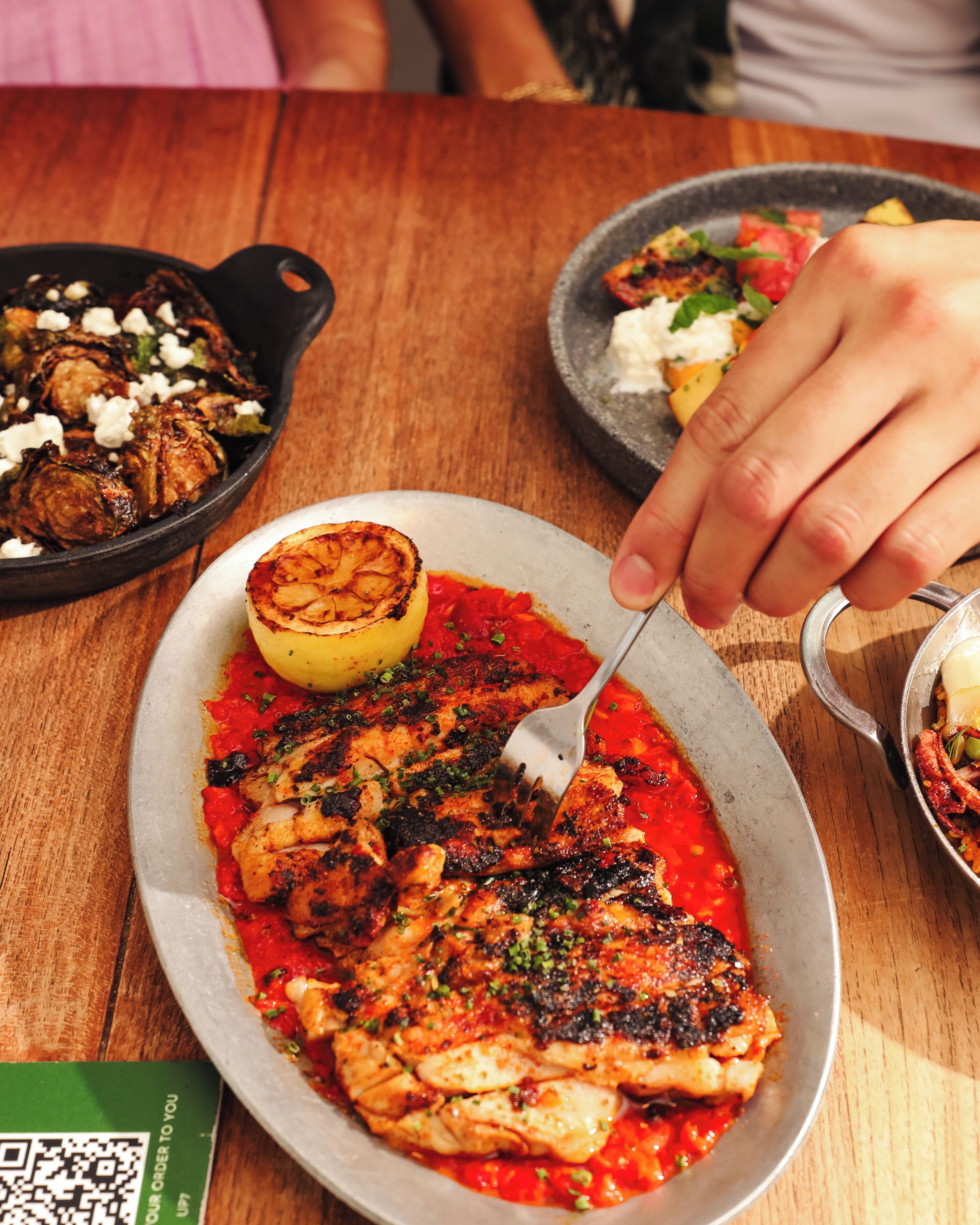A dining table with a plate of food, a QR code, and a QR code on a green card.