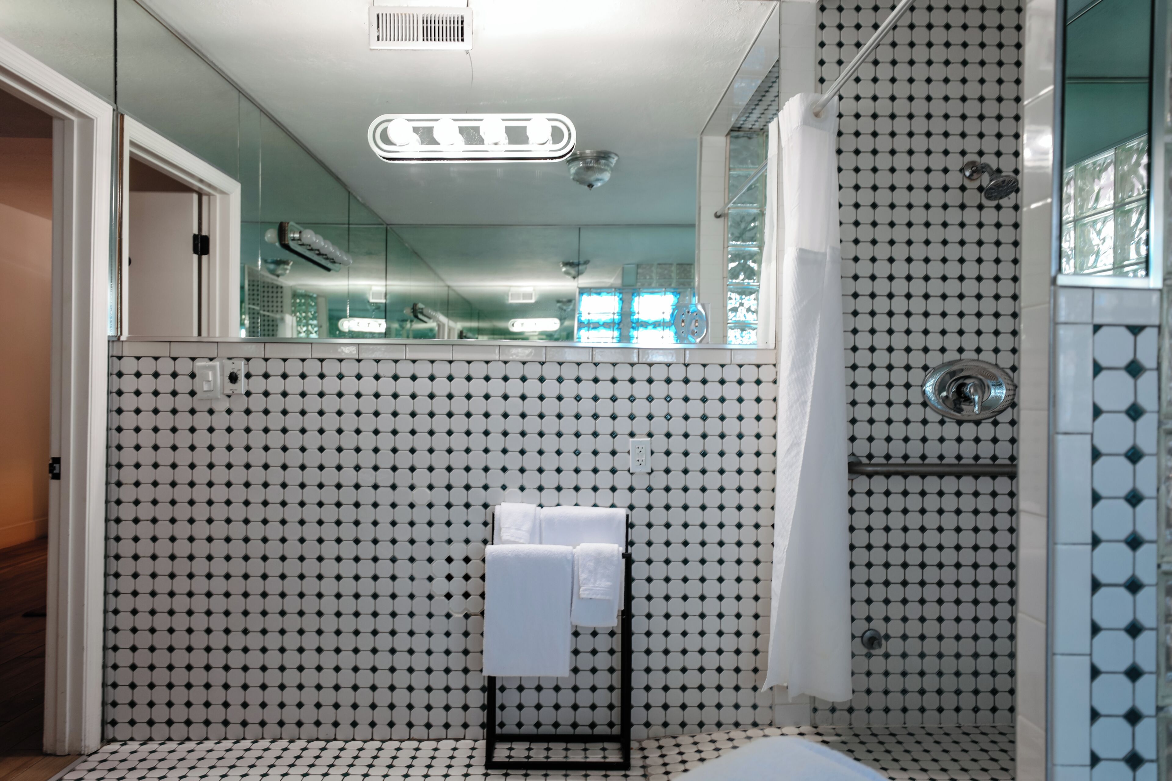 A bathroom with a tiled floor, a glass shower enclosure, and a towel rack with towels.
