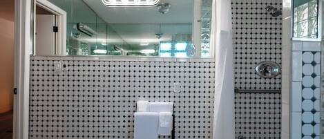 A bathroom with a tiled floor, a glass shower enclosure, and a towel rack with towels.