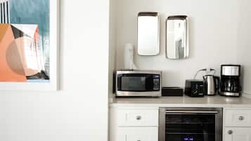 A modern kitchen with a microwave, coffee maker, and oven. There are two wall mirrors and a framed artwork above the counter.