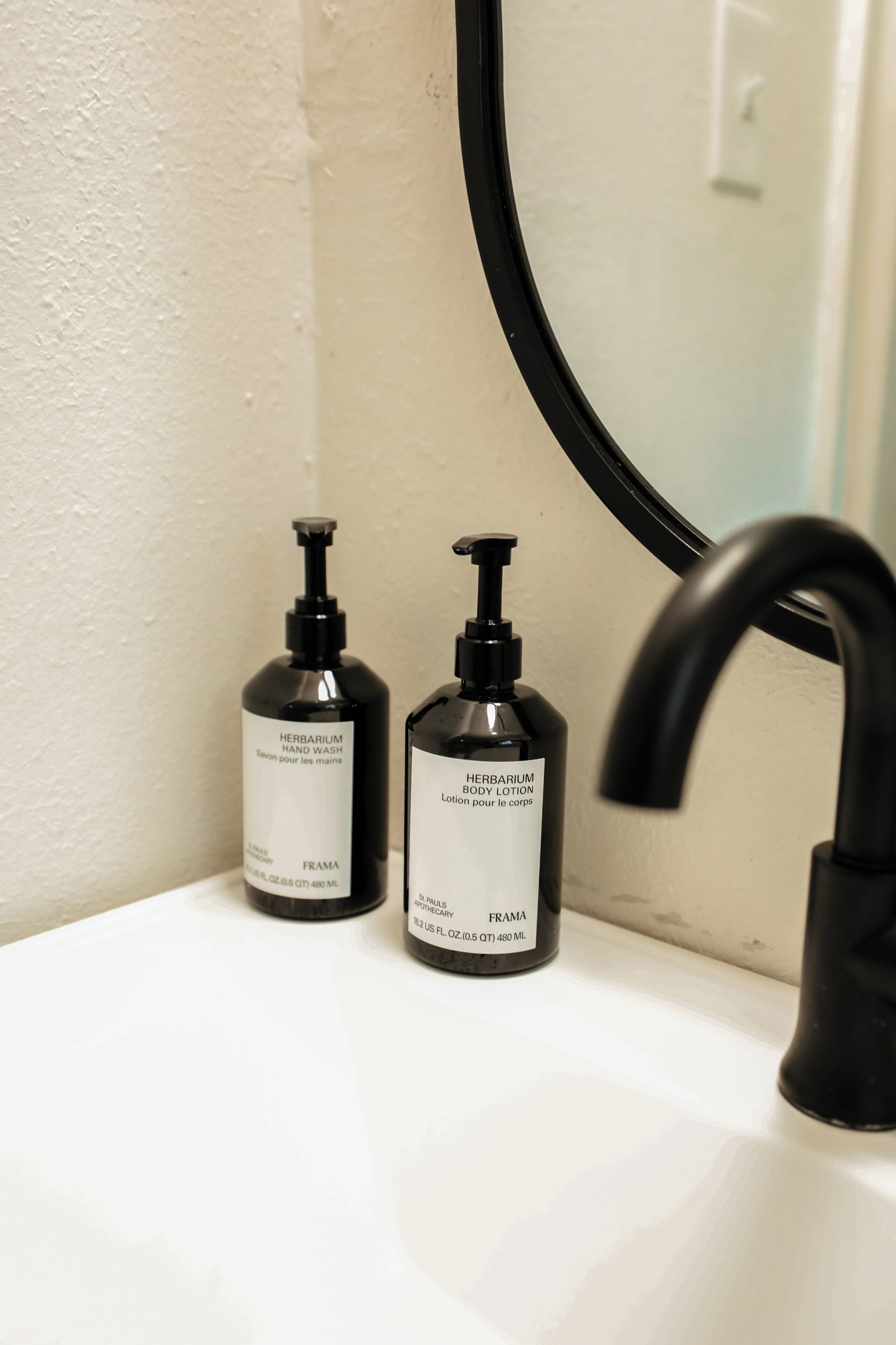 Un lavabo de salle de bain avec deux flacons de lotion pour le corps et un savon pour les mains.