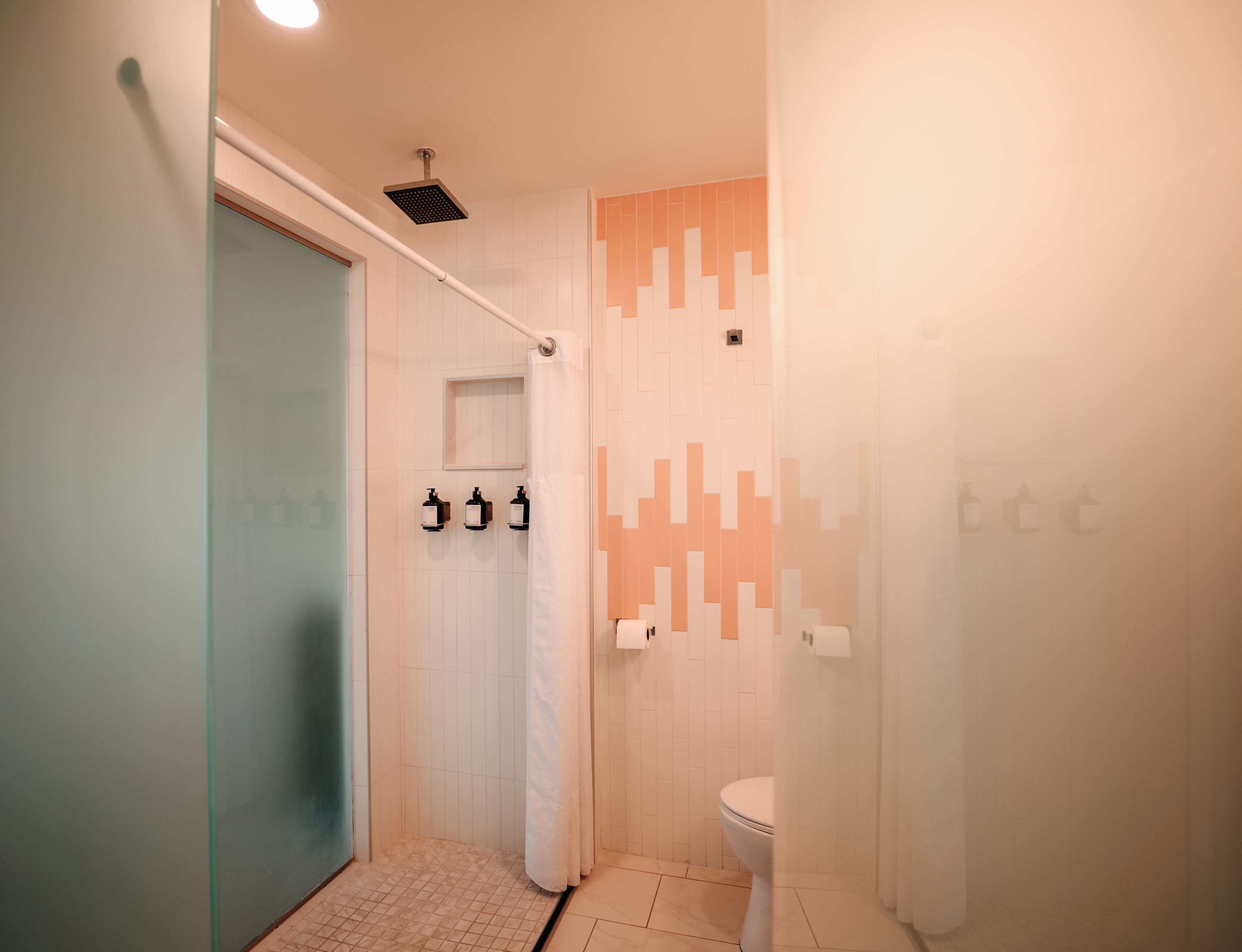 A modern bathroom with a shower, toilet, and a glass partition wall.