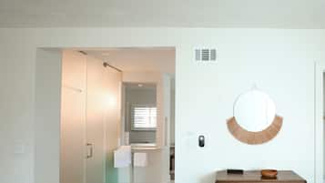 Um interior moderno com uma cômoda de madeira, um espelho redondo e um chão de azulejos.
