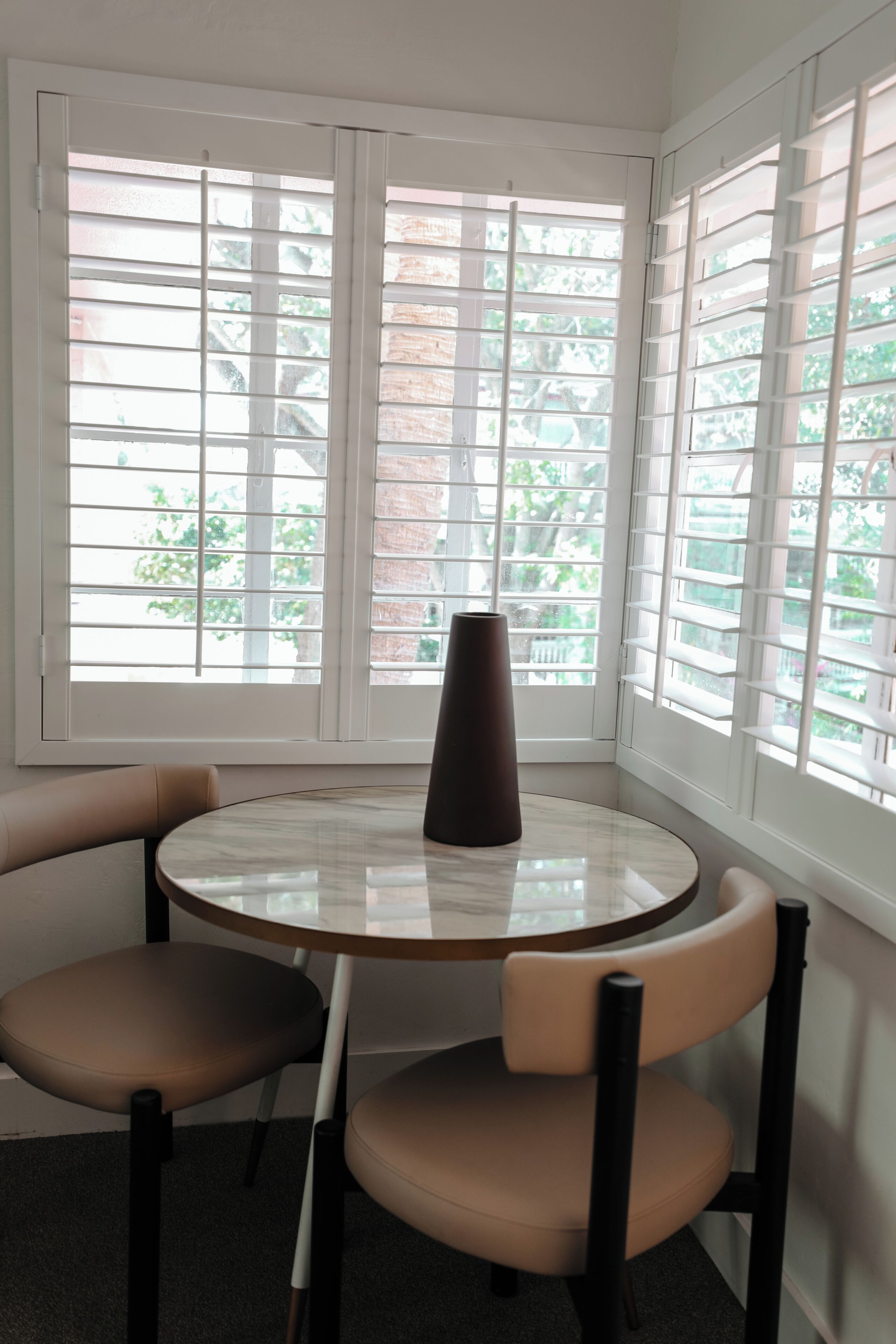 A room with a round table, two chairs, and a vase.
