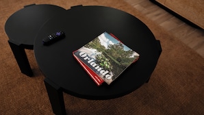 Uma mesa preta com um livro chamado 'Orlando' e um controle remoto.