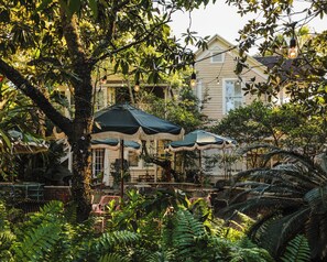 A courtyard with outdoor seating, umbrellas, and a building with a balcony. -  Suites by The Wellborn (Orlando)