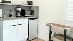 Uma cozinha compacta equipada com micro-ondas, máquina de café e pequena geladeira.
