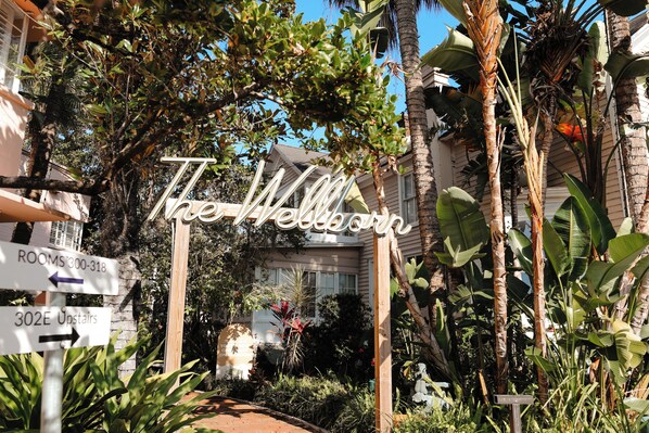 A sign with 'The Wellborn' written on it, surrounded by lush greenery and a building in the background. -  Suites by The Wellborn (Orlando)