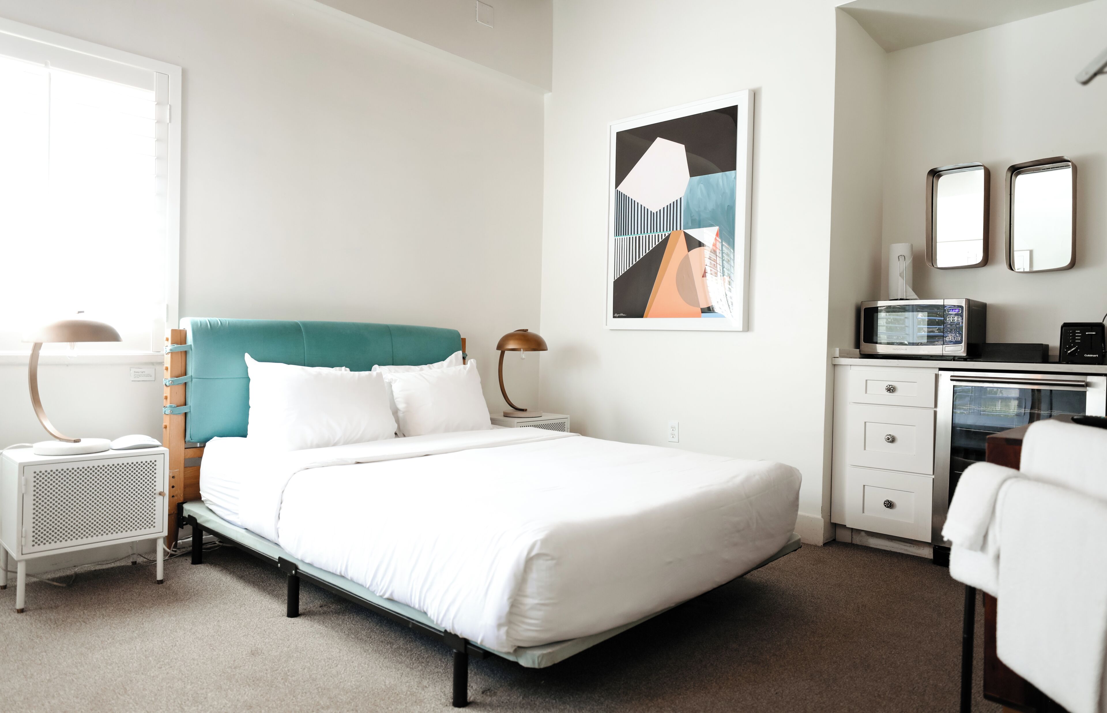 Une chambre moderne équipée d’un lit, de tables de chevet, d’un bureau et d’un four à micro-ondes.