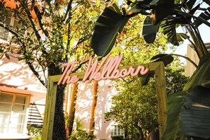 A wooden sign with the text 'The Wellborn' in a cursive font, surrounded by lush greenery and trees.