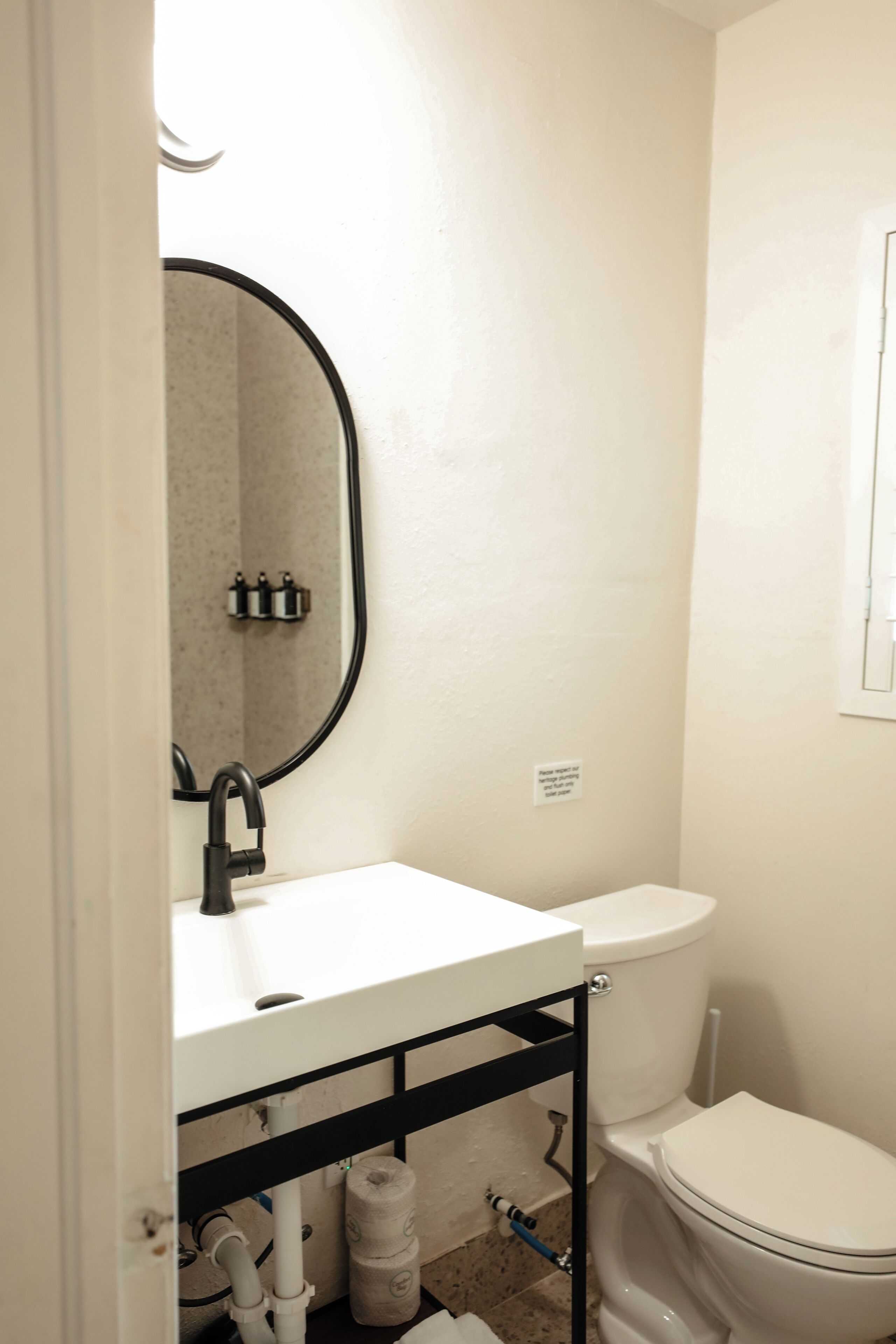 A bathroom with a white sink, black faucet, and a toilet.