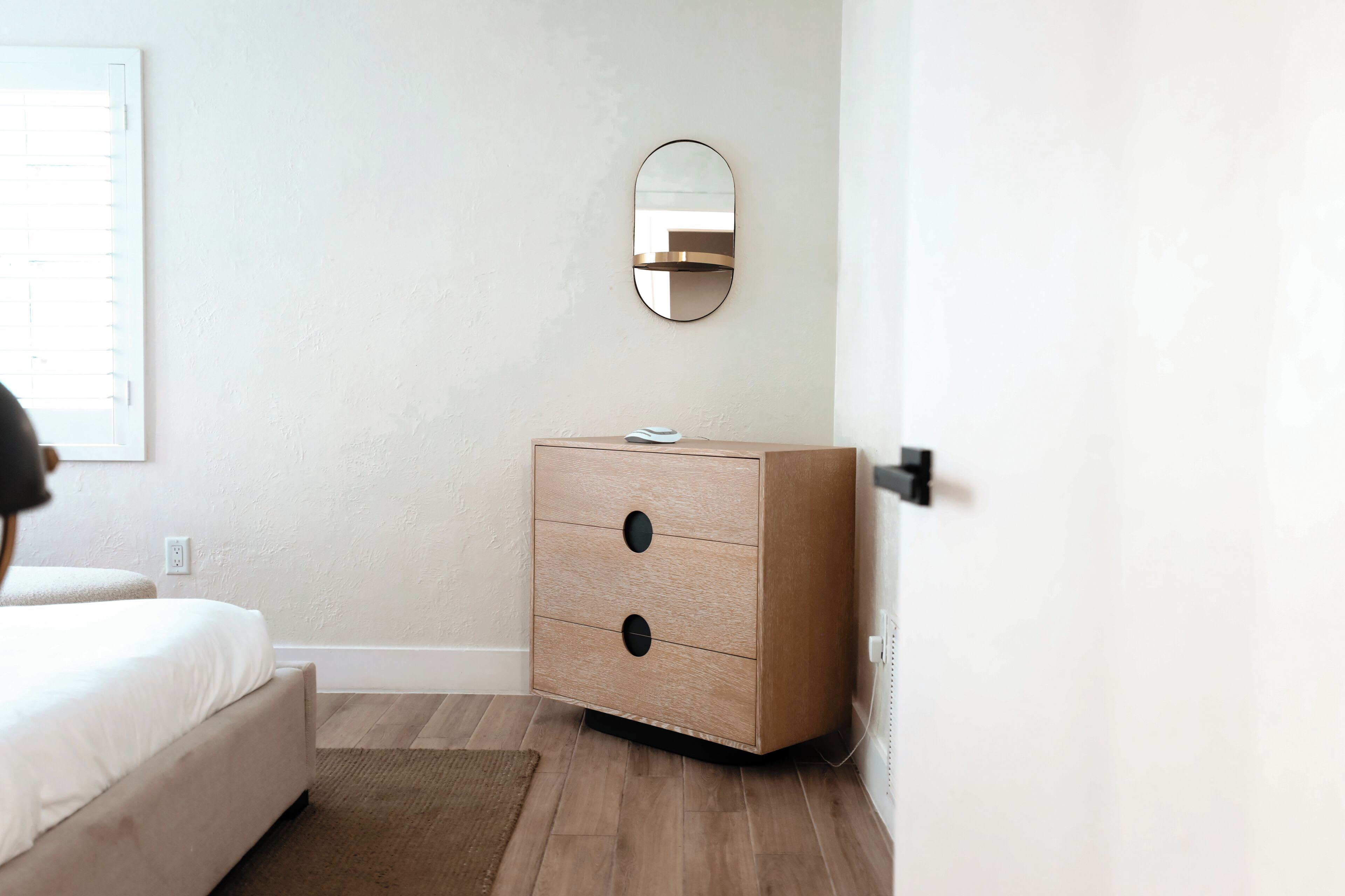 A bedroom with a bed, a dresser, a mirror, and a door.