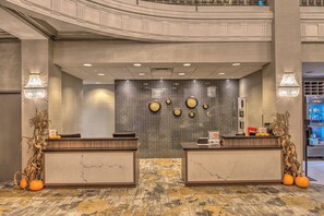 Un área de recepción con mostradores de mármol, una pared decorativa con espejos circulares y un piso con diseño.