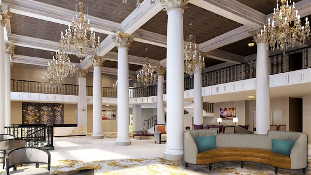 A spacious lobby with high ceilings, ornate chandeliers, and a central seating area. - DoubleTree by Hilton Utica (Utica)