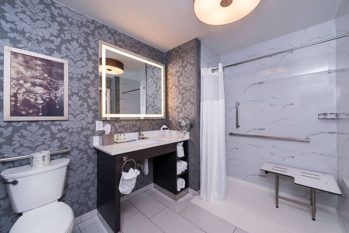 A modern bathroom with a toilet, sink, mirror, and shower.