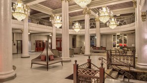 A grand lobby with high ceilings, ornate chandeliers, and a central seating area with sofas and a daybed. - DoubleTree by Hilton Utica (Utica)
