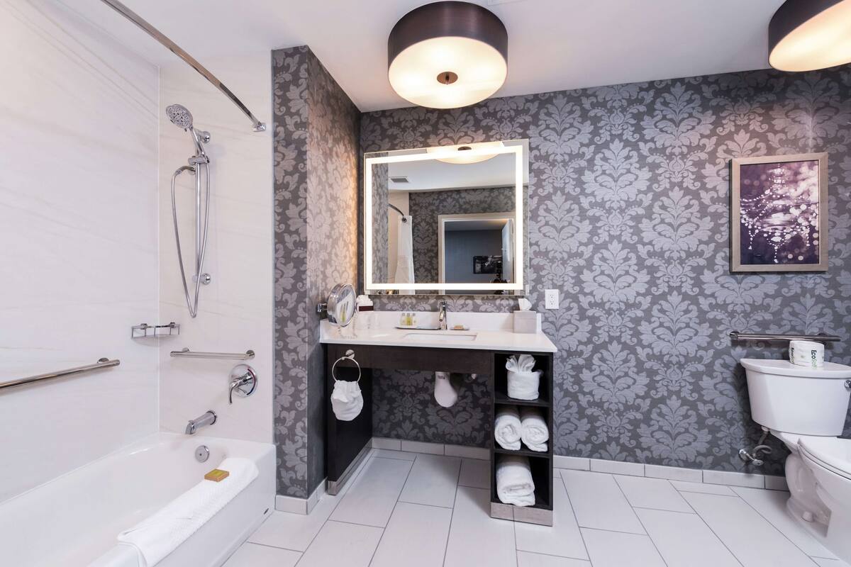 A modern bathroom with a bathtub, vanity with a mirror, and a toilet.