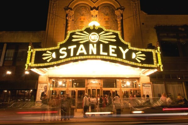 Un cartel de cine con el nombre "STANLEY" y un logotipo, rodeado de gente.