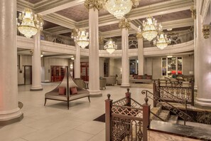 Un lobby espacioso con varios niveles, candelabros ornamentales y una zona de estar central con sofás y una estructura de cama original.