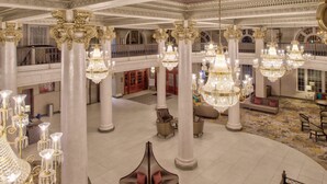A grand lobby with ornate chandeliers, high ceilings, and classical columns. - DoubleTree by Hilton Utica (Utica)