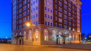 A multi-story building with a classic architectural style, featuring arched windows and a balcony on the ground floor. - DoubleTree by Hilton Utica (Utica)