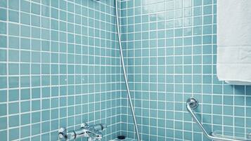 Une salle de bain avec une baignoire, une douche et un mur carrelé.