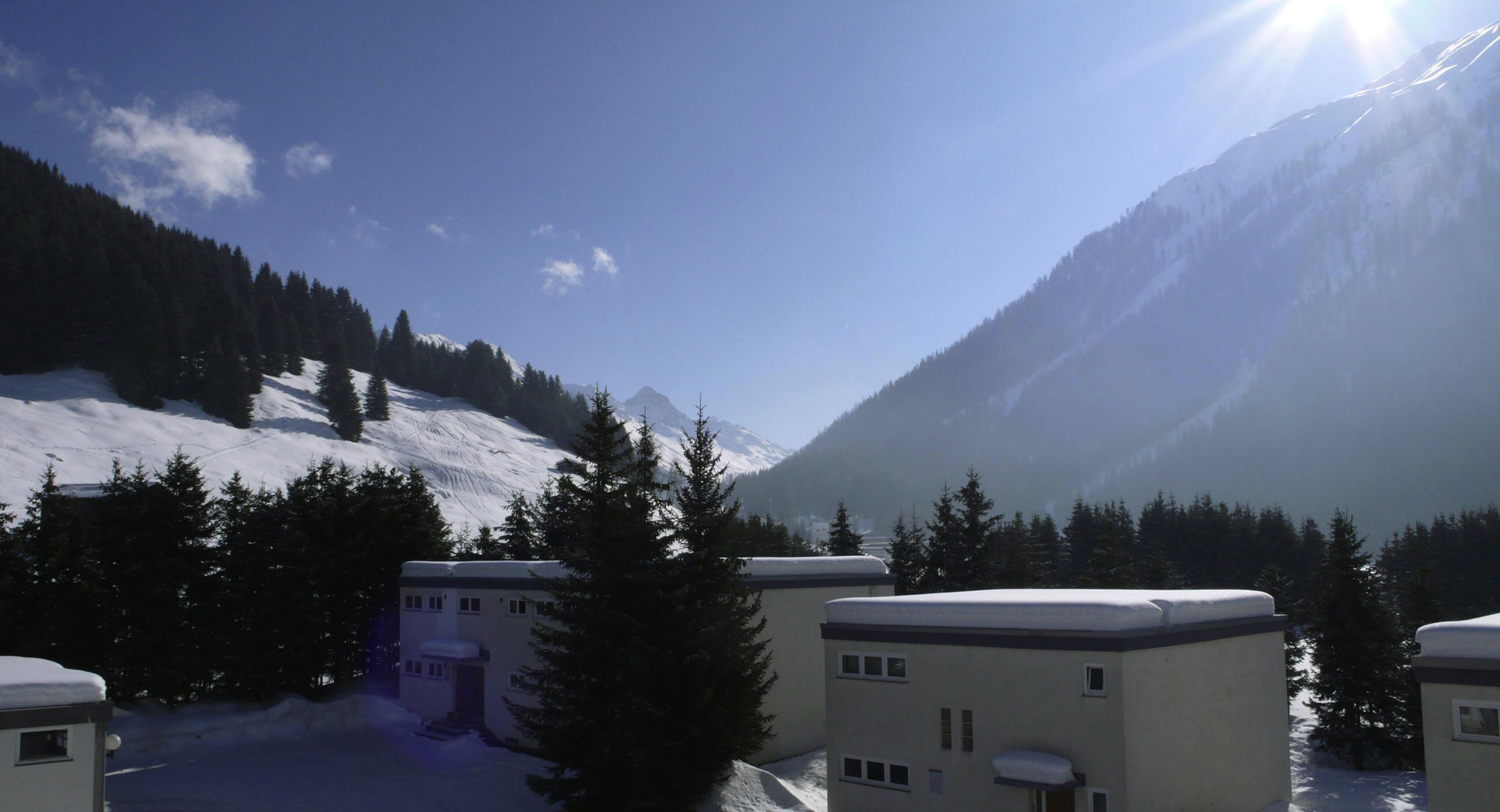 A snow-covered mountain landscape with buildings in the foreground.