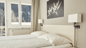 Una habitación de hotel con cama, mesitas de noche, ventana y una obra de arte colgada en la pared.