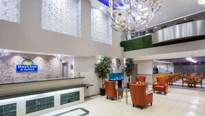 Een hotel lobby met een receptiebalie, een zithoek en een restaurant.