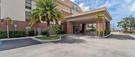 A Days Inn 5 Suites building with a covered entrance, palm trees, and a parking lot.