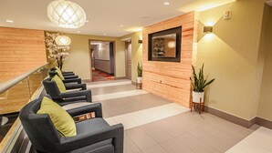 Een moderne lobby met een trap, zithoek en een receptiebalie.