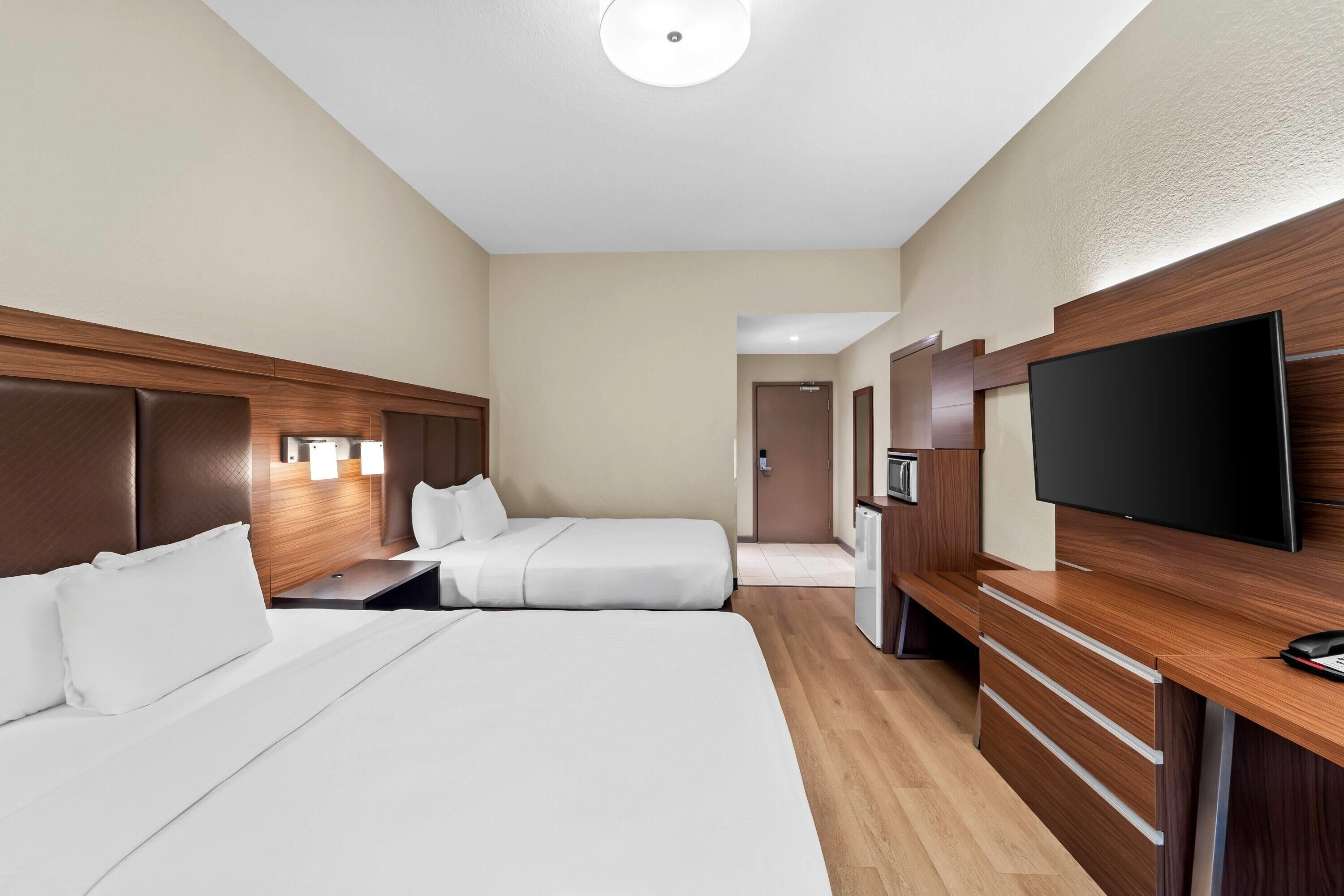 Une chambre d’hôtel avec deux lits, une télévision, un bureau et un mini-bar.