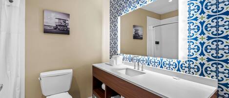 A bathroom with a white toilet, a wooden vanity with a white sink, and a large mirror.