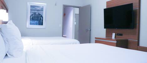 A hotel room with two beds, a flat-screen TV mounted on the wall, and a framed picture on the wall.